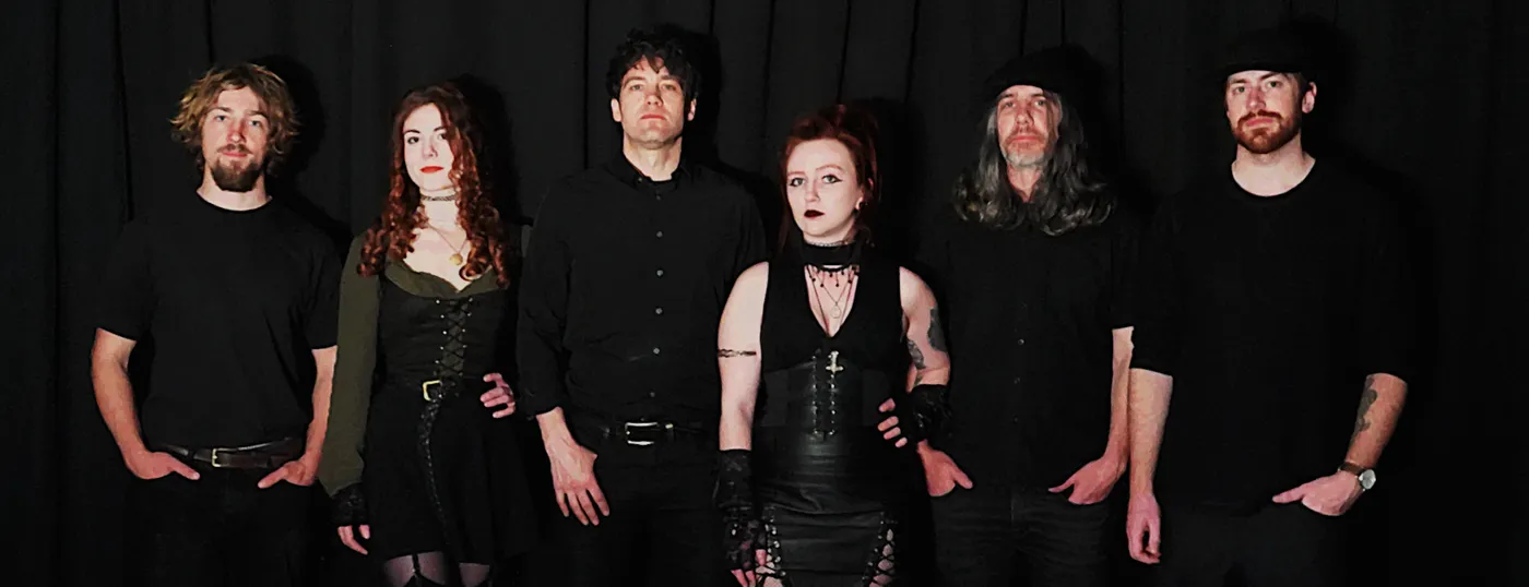The band as a six piece, standing against a dark backdrop